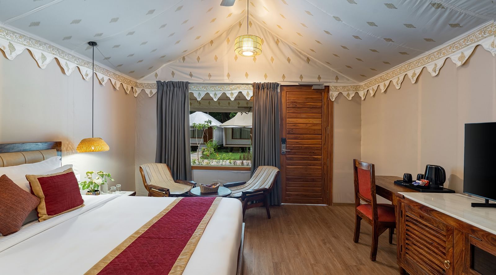 full view of the luxury tent villa with a family seating area and a huge window at the far end of the room at aranya vilas