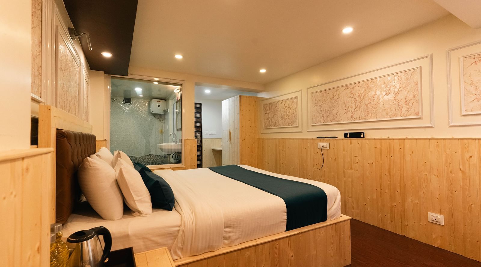 an image of a bedroom with a tea and coffee maker at an image of a bedroom reflected through a bathroom mirror showcasing a bed with soft lighting at Avianna New Mandala Hotel & Spa, Darjeeling.