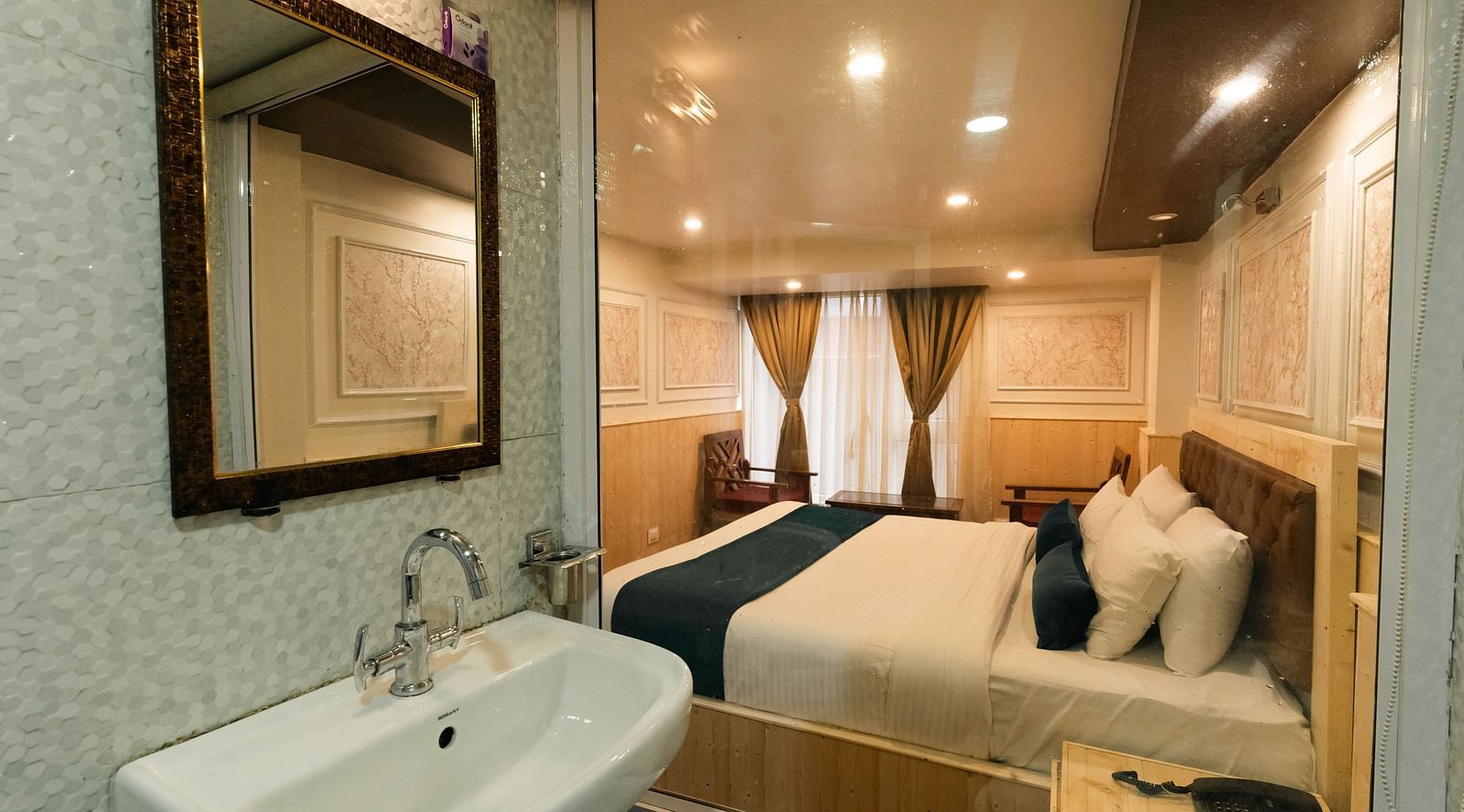 an image of a bedroom reflected through a bathroom mirror showcasing a bed with soft lighting at Avianna New Mandala Hotel & Spa, Darjeeling.