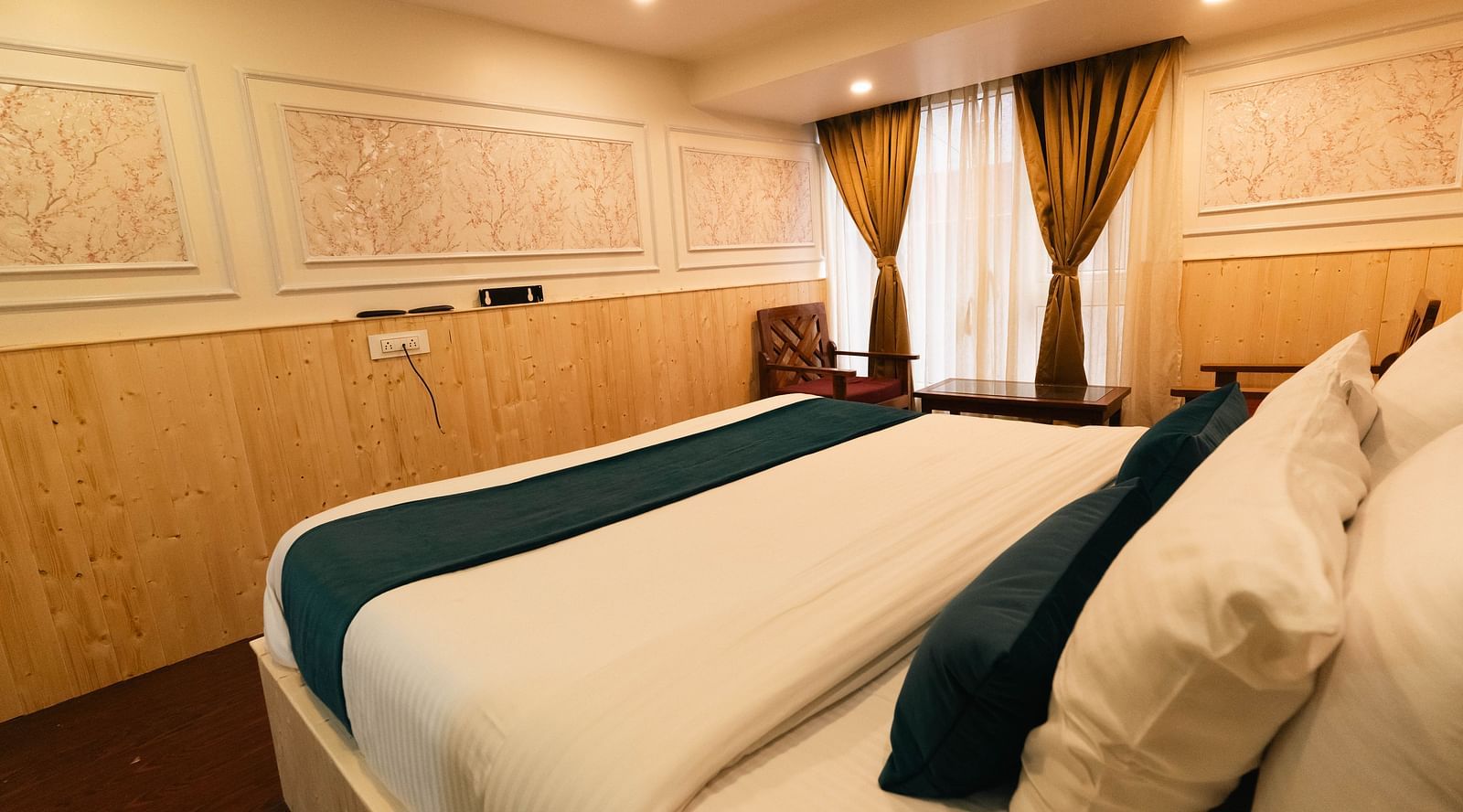 an image of a side view of a bedroom with pillows at an image of a bedroom reflected through a bathroom mirror showcasing a bed with soft lighting at Avianna New Mandala Hotel & Spa, Darjeeling.