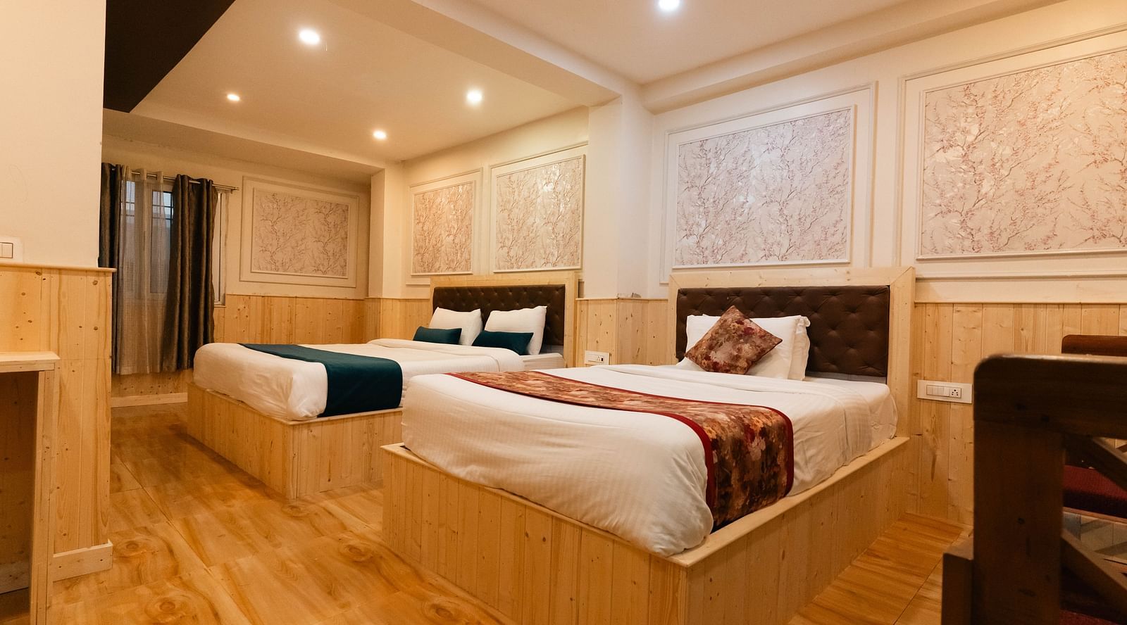 an image of a bedroom with one king size bed and one single bed placed closely at an image of a bedroom with wooden strips flooring at Avianna New Mandala Hotel & Spa, Darjeeling.