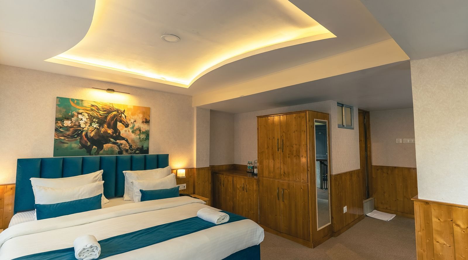Deluxe Room with a king size bed, inviting ambiance, wooden bedside table, and wooden cupboard at Avianna Seven Seas, Darjeeling.