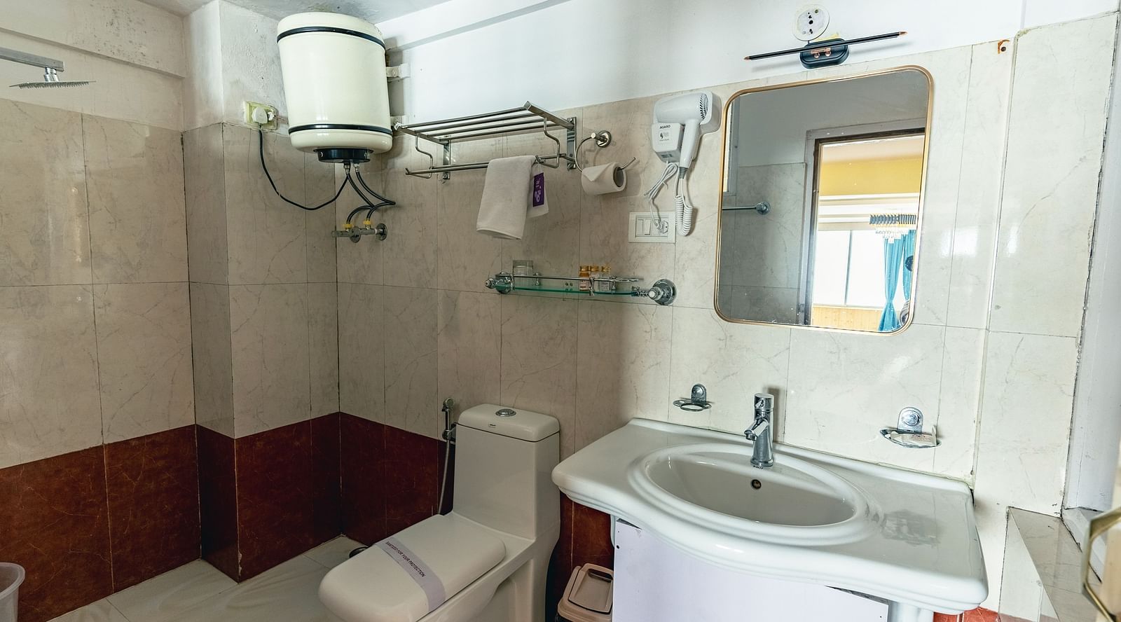 Deluxe rooms bathroom equipped with a washbasin, mirror, geyser, and western toilet3