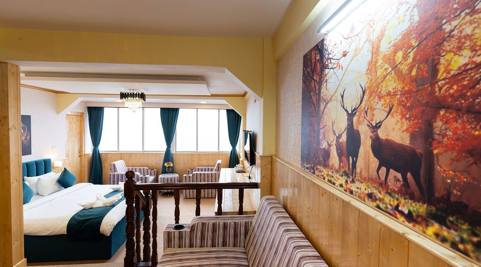 Suite with a king size bed, wall-mounted television, wooden table, and cosy lighting along with attached living room at Avianna Seven Seas, Darjeeling