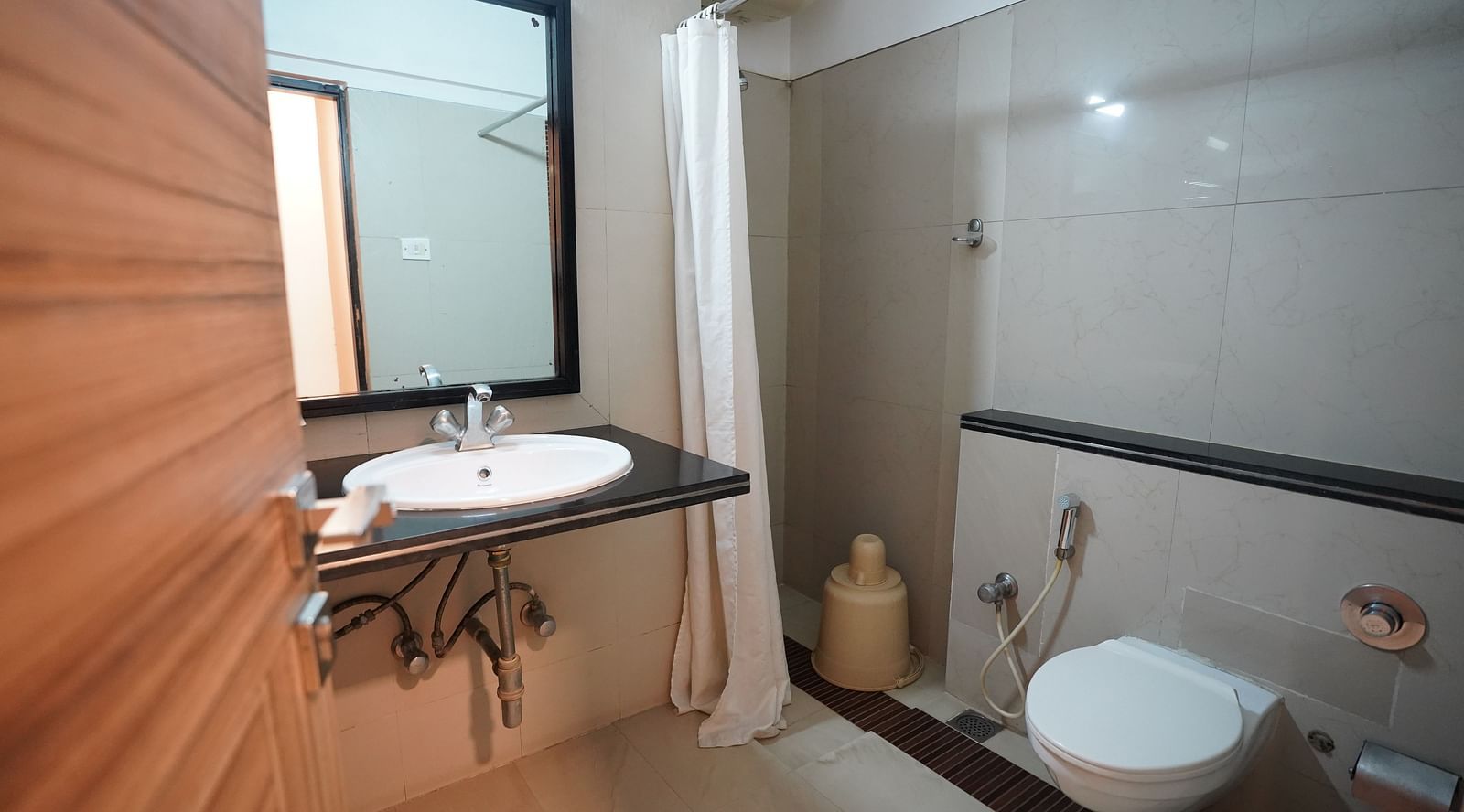 an image of bathroom of deluxe room with wash basin and a mirror at  City Centre Residency, Bangalore