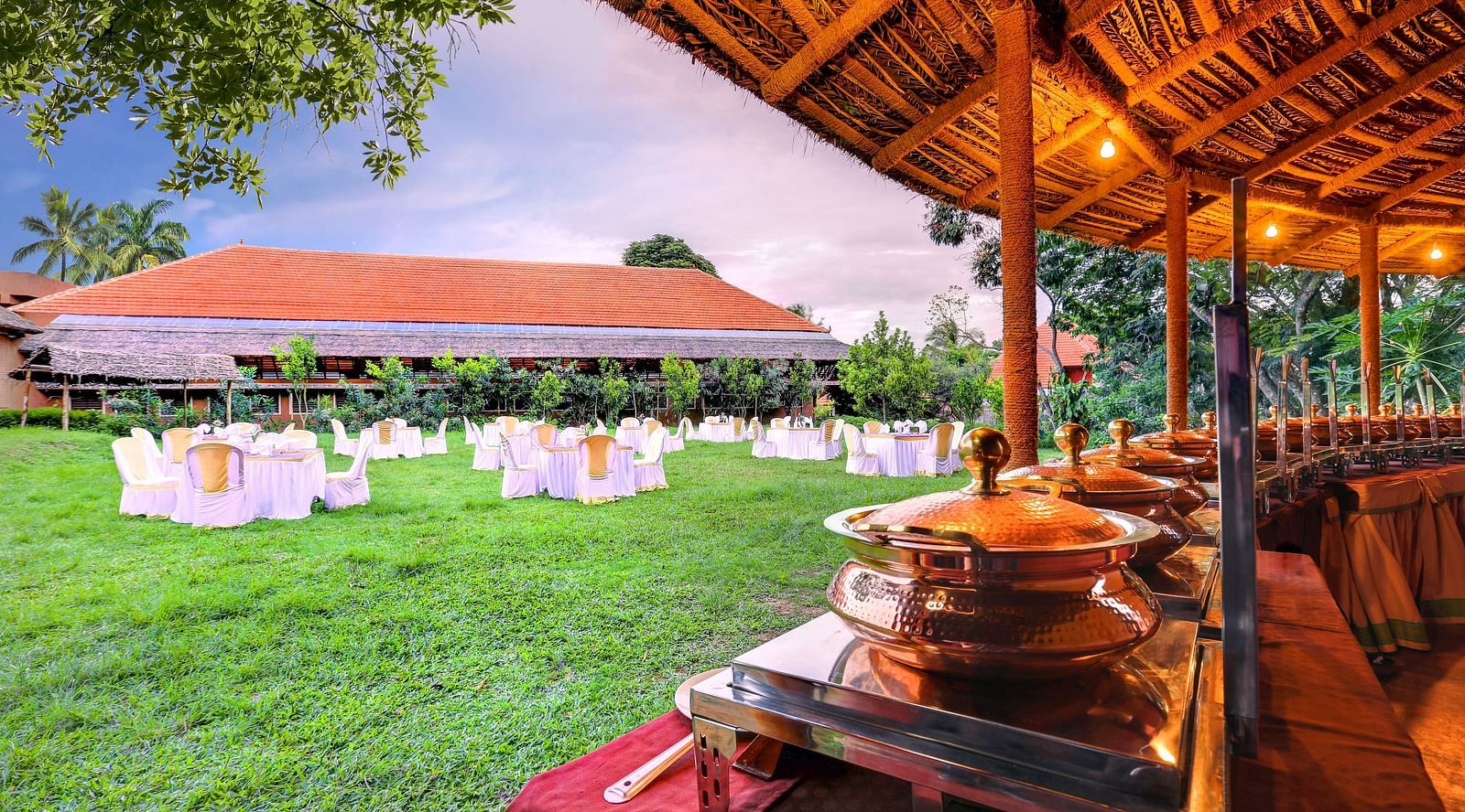 An overview of the lawn area as seen from the restaurant with elaborate seating arrangements at hoysala village resort.