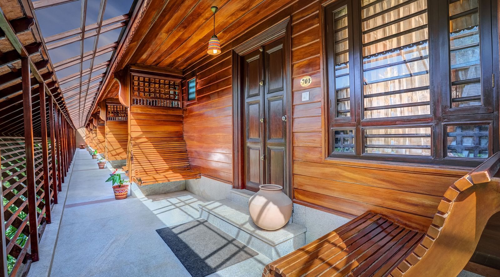 An image of a wooden balcony where an arm chair is kept - Hoysala Village Resort, Hassan