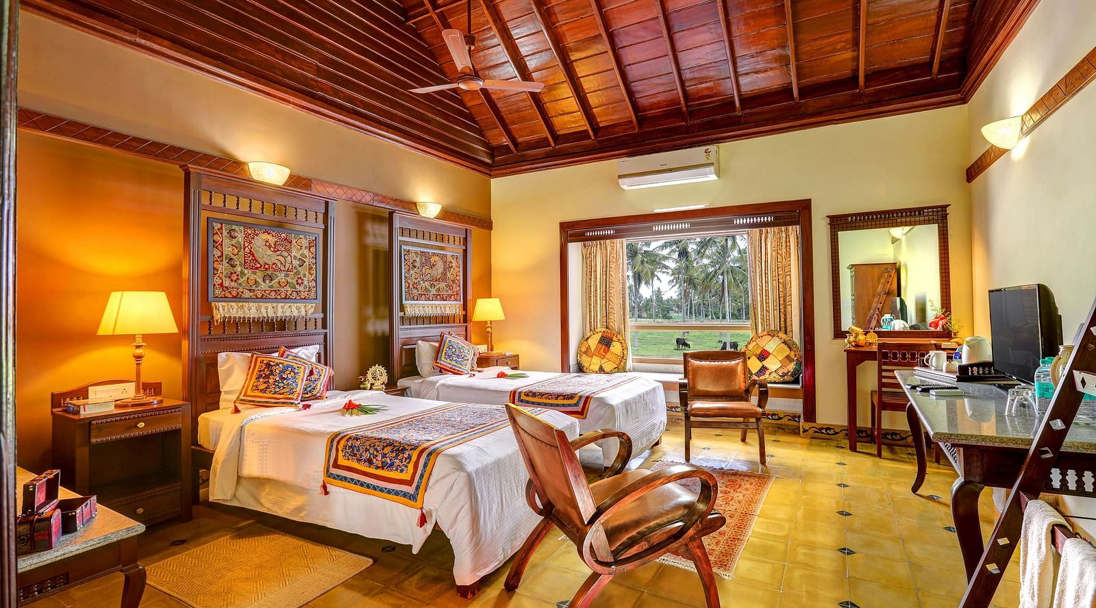 An image of a bedroom with seating area, open windows, lamp, dressing table, etc. -  Hoysala Village Resort, Hassan
