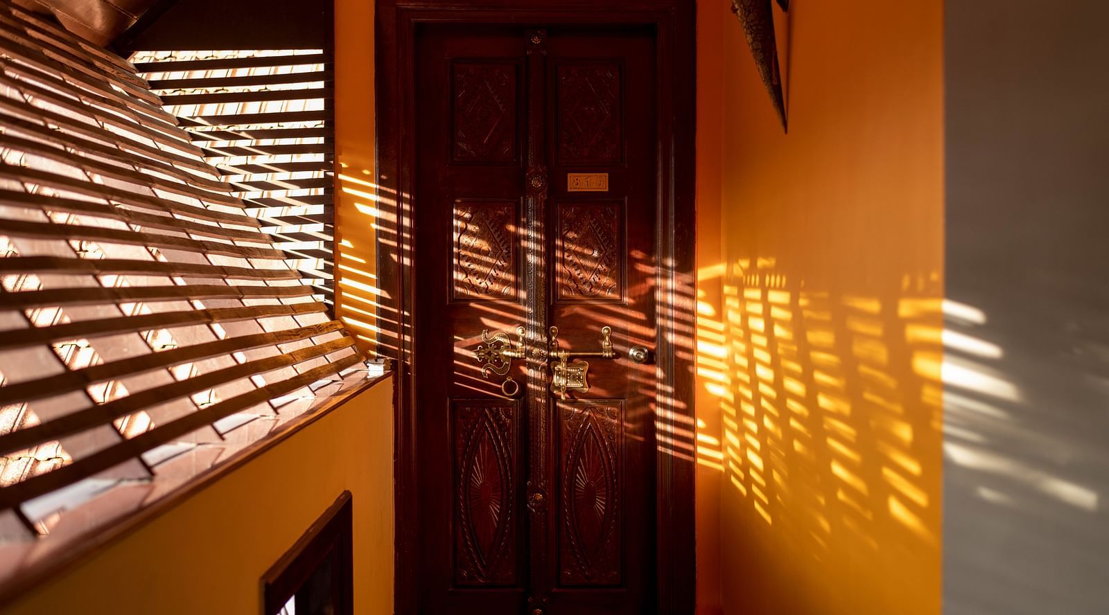 image of a wooden door with sunlight falling over it at hoysala village resort, hassan