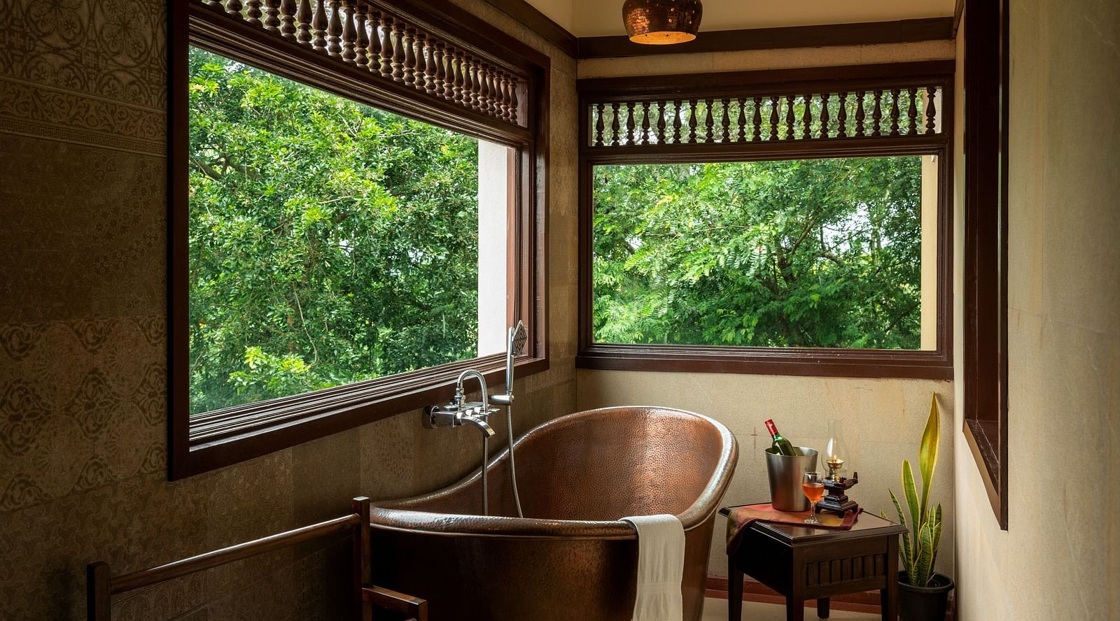 image of a copper bathtub with large glass windows at side at malnad attic suite -hoysala village resort, hassan