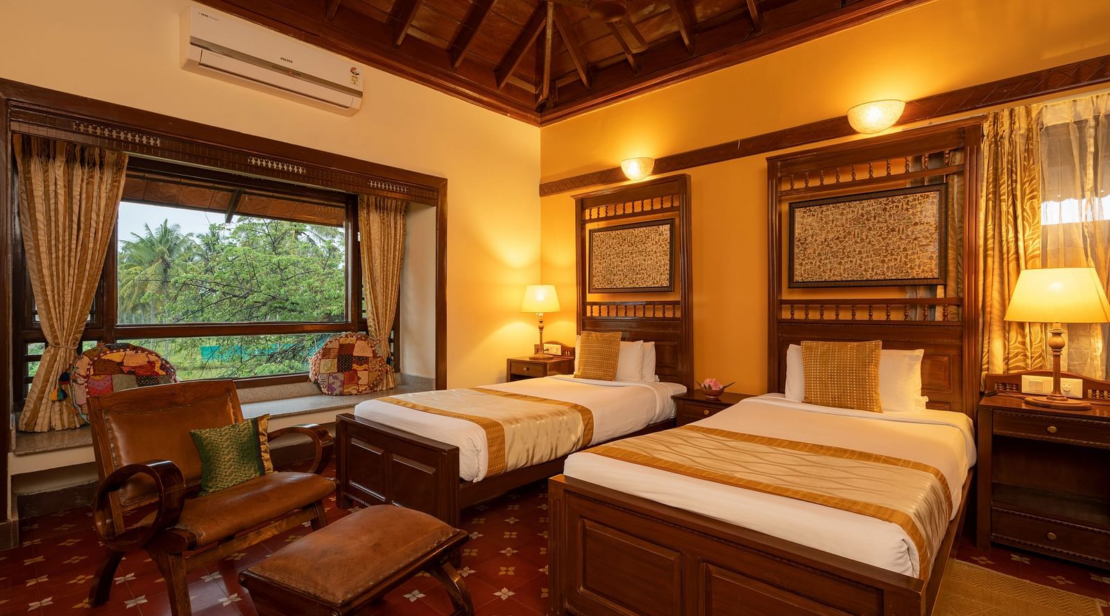 An image of a bedroom with a table lamp, a huge artistic photo frame, twin beds, and other wooden furnishings - Hoysala Village Resort, Hassan