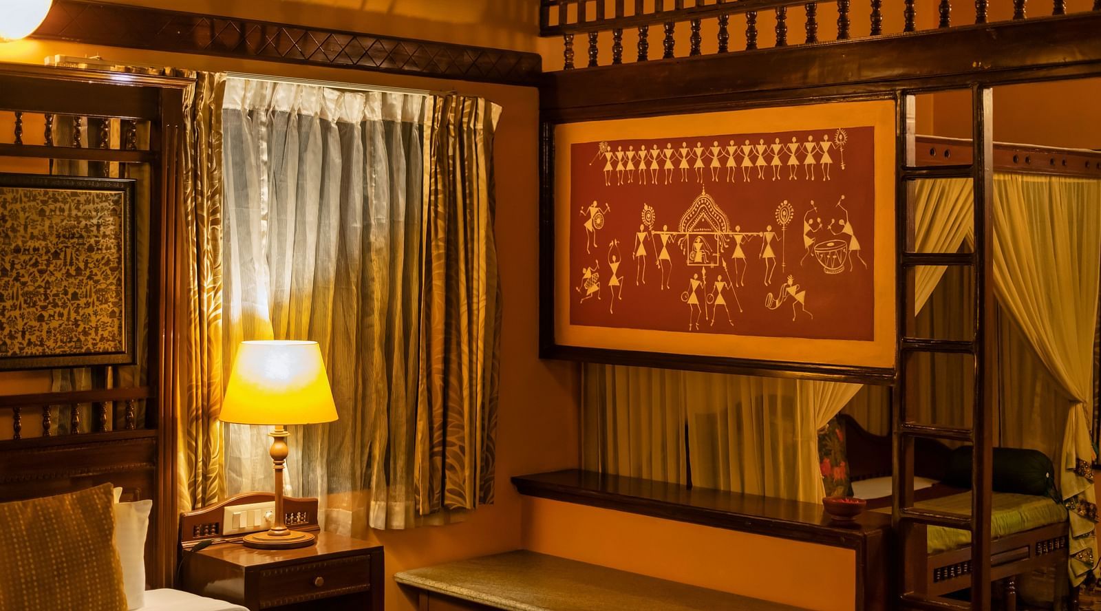 An image of a bedroom with a table lamp, a huge artistic photo frame, a poster bed, and other wooden furnishings - Hoysala Village Resort, Hassan
