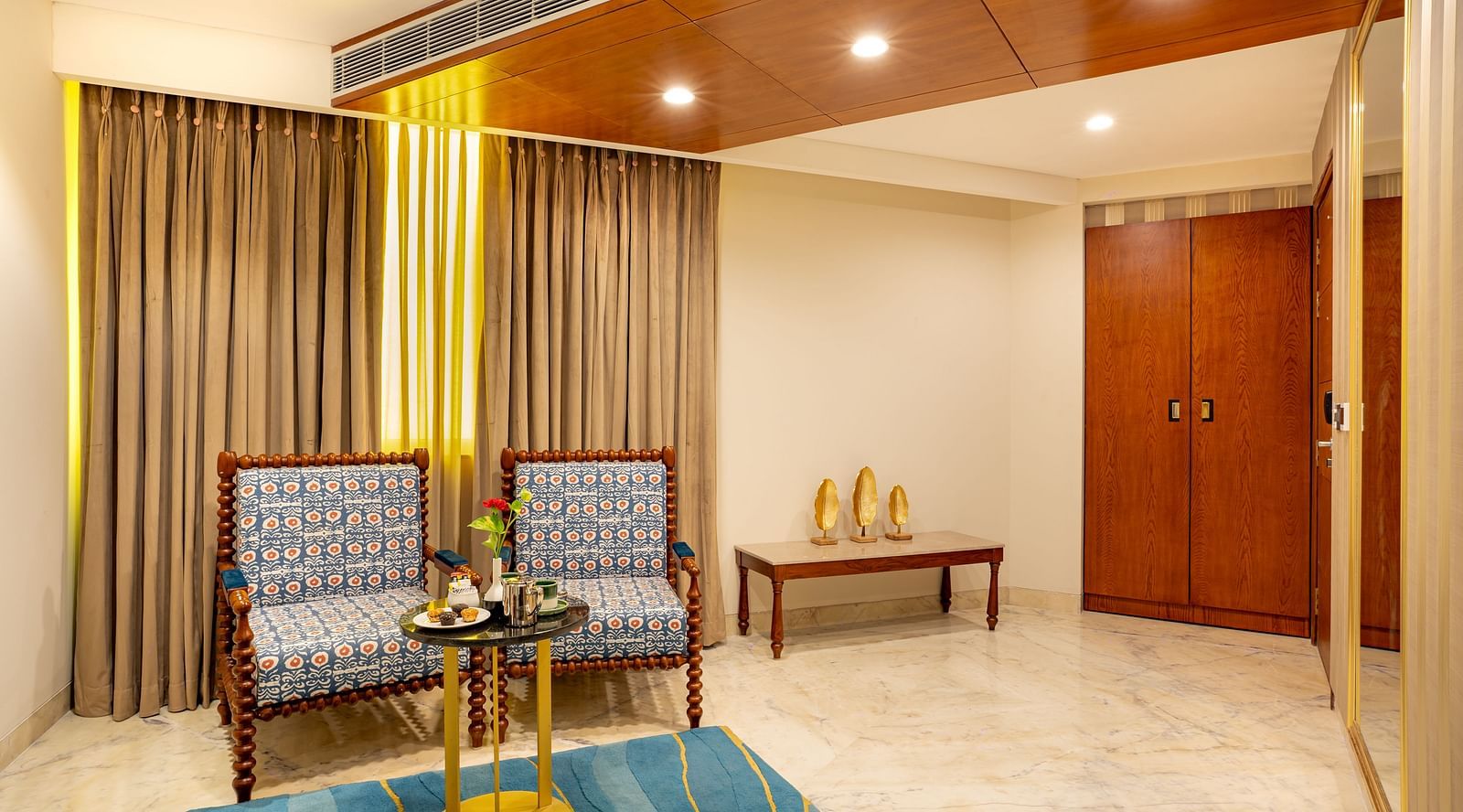 Two cushion seatingTwo cushioned seats with a wooden decorative round table and a rectangular side table in the Suite at Inde Signature Jaipur with a wooden decorative round table and side rectangle table in Suite at Inde SIgnature Jaipur