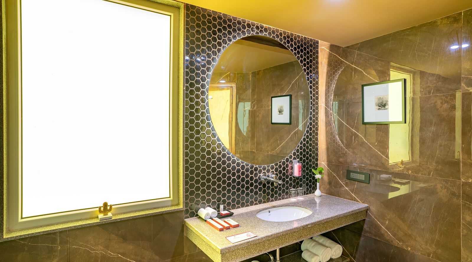 Large circular mirror above the washbasin in the bathroom of the Suite at Inde Signature Jaipur.