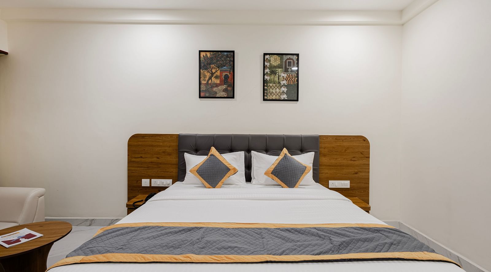 Front view of a king-size bed with clean white linen and accent cushions at Lemonridge Hotels, IDPL Balanagar.