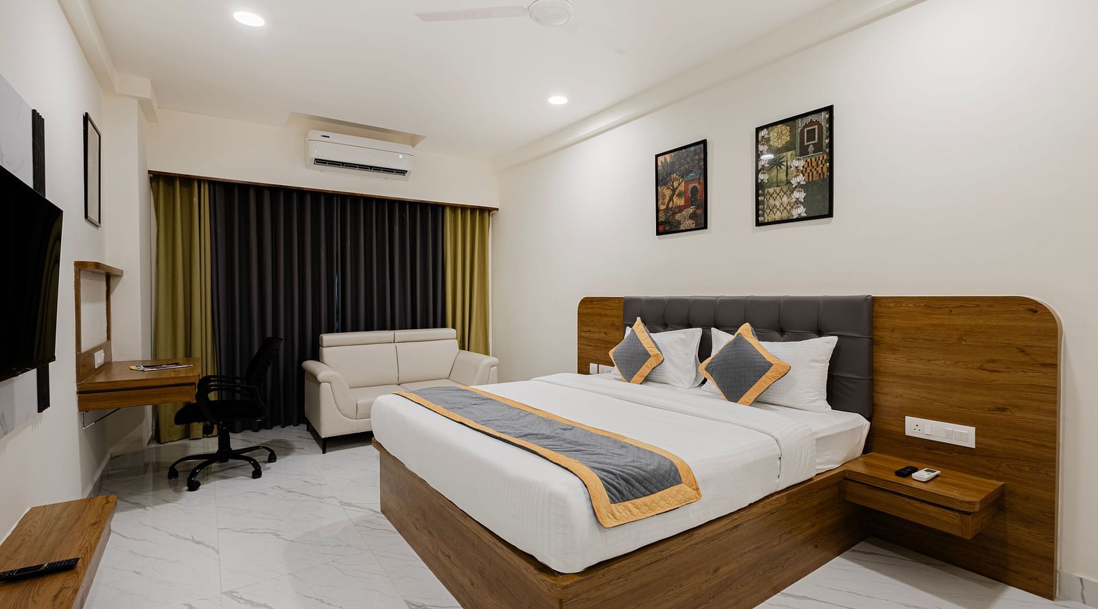 Spacious premium room with king bed, seating area, and warm lighting at Lemonridge Hotels, IDPL Balanagar.