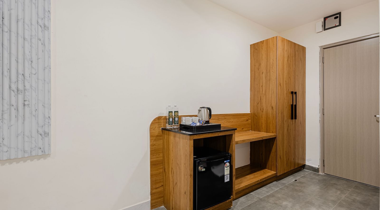 Compact refreshment corner with mini fridge and kettle at Lemonridge Hotels, IDPL Balanagar.