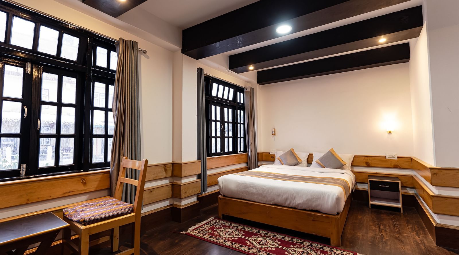 view of the deluxe room with a large bed and a chair with a window in the background at Mystique Valley Resort  