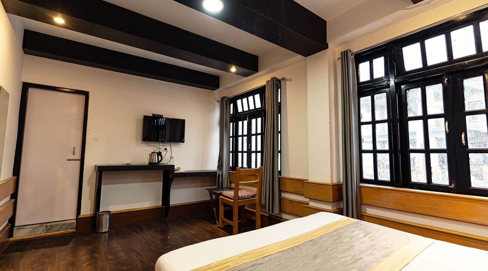 view of the deluxe room with a large bed and a chair with a window in the background at Mystique Valley Resort  