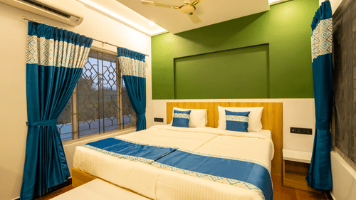 A room featuring two single beds put together, a view of a window outside and well lit ambience - MGM Whispering  Nest