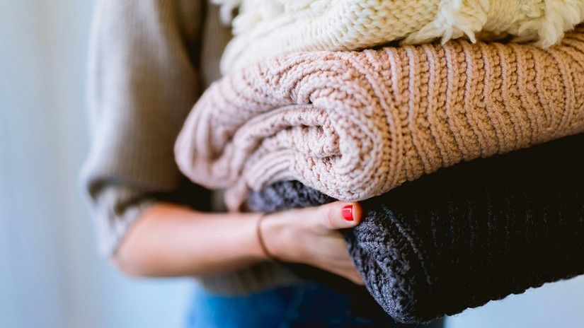 A woman holding neatly folded clothes, symbolizing fresh laundry and cleanliness