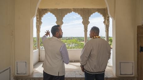Two individuals stand in an arched opening, looking out at the landscape from Fort Barli, Ajmer.