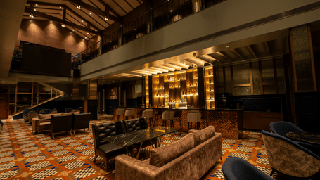Indoor bar lounge with sofas, tables, and ceiling lights at Origyn, Merlis Hotel, Coimbatore.