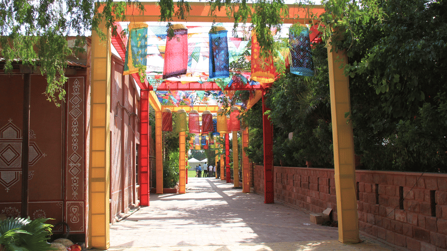 A paved outdoor walkway featuring a series of archways holding colourful banners at Garh Govind.