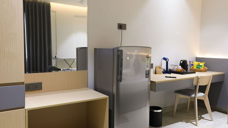 Compact work desk, mini fridge, and mirror setup inside a room at Hotel Kyzen HiTech City – Your Zenly Stay.