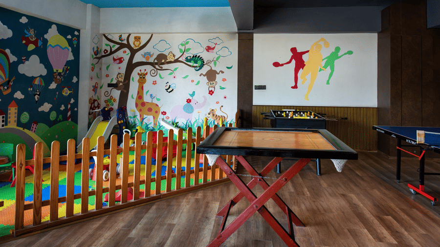 An indoor soft play area with a carrom board and play school wall art at Hotel Sonar Bangla, Taki.