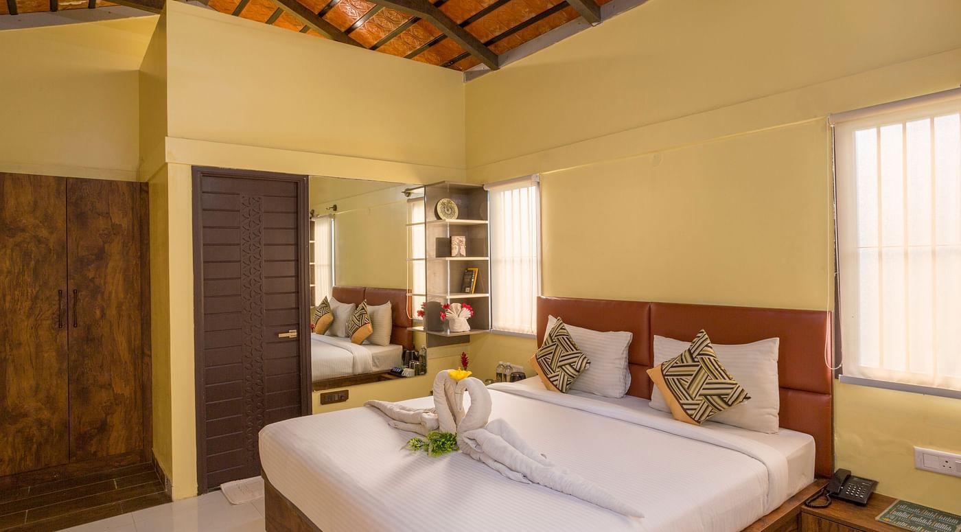 Cosy bedroom with elegant decor and wooden furnishings – Nirantara Resort & Spa