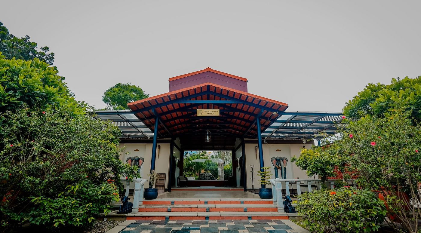 The entrance to a building with a tiled roof and steps leading up, possibly at Nirantara Resort & Spa in Bengaluru.