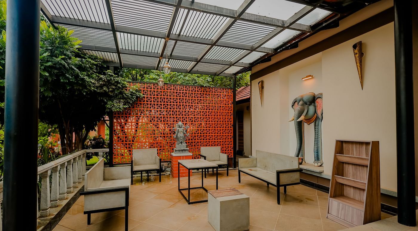 Two people playing table tennis in a well-lit room with large windows at Nirantara Resort & Spa.