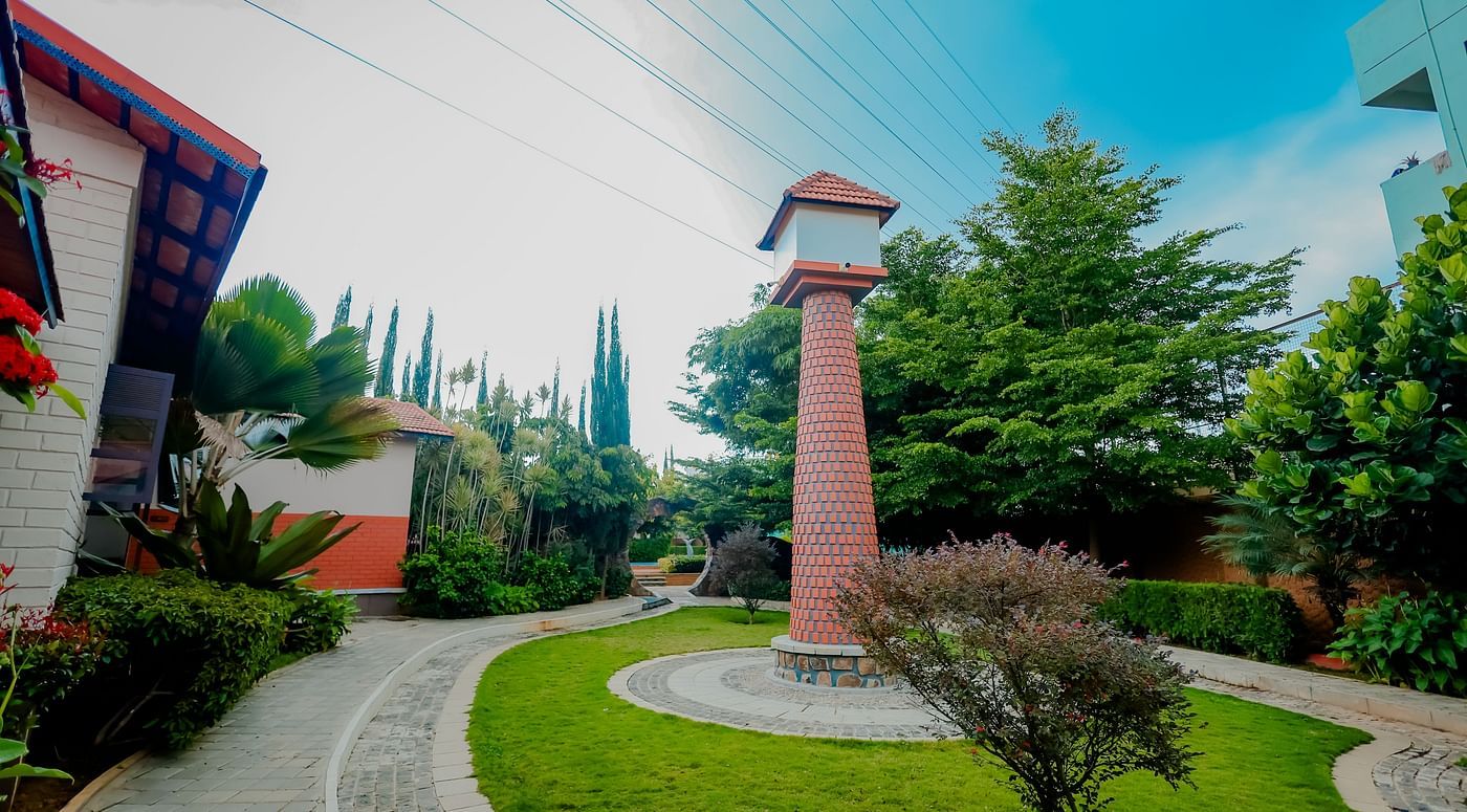 The grounds of Nirantara Resort & Spa with a clock tower, landscaped gardens, and pathways.