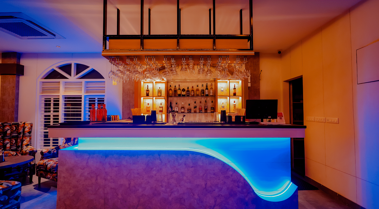 The stylish bar area at Nirantara Resort & Spa, featuring modern lighting, comfortable seating, and a wide selection of beverages.