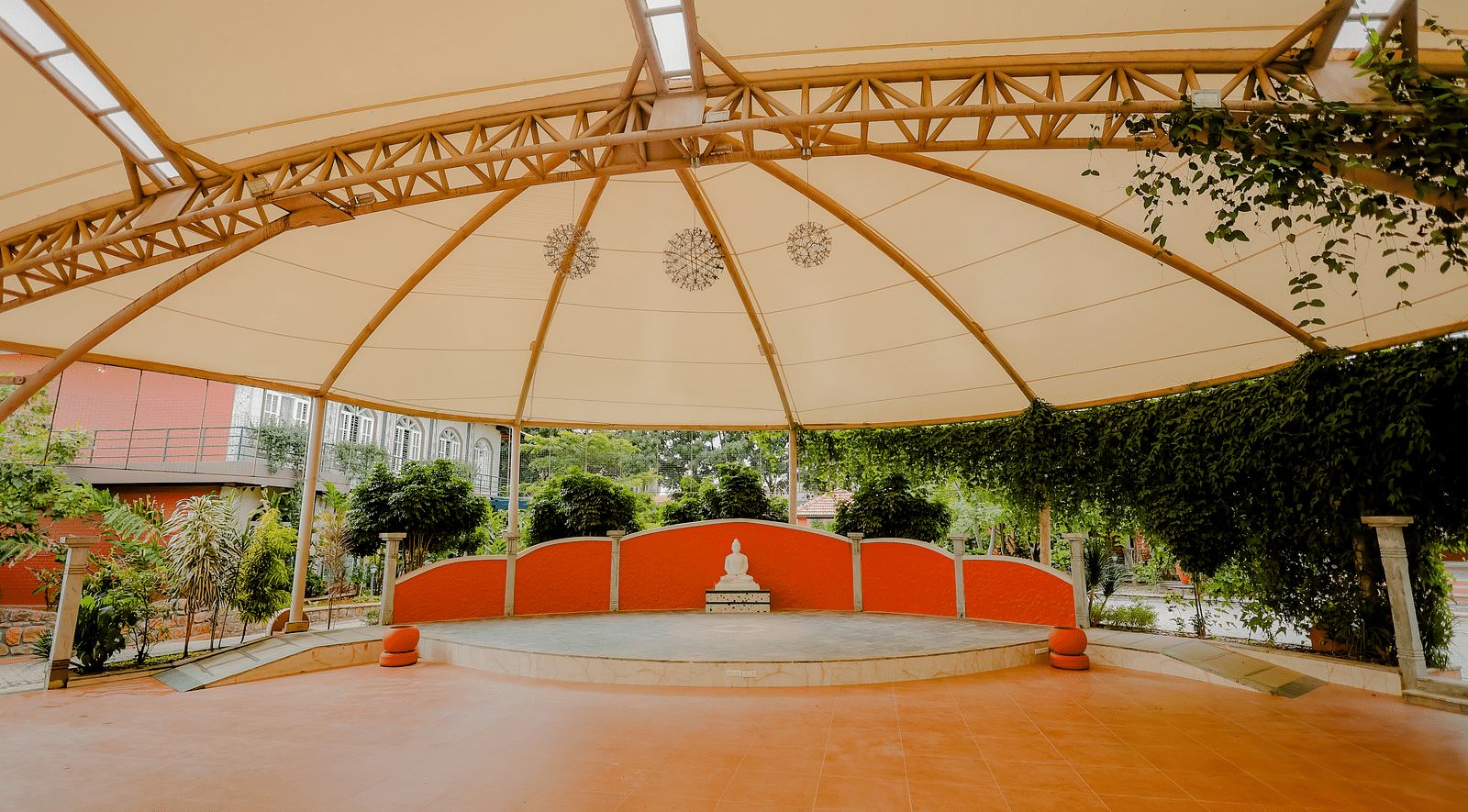 An outdoor event space with a large canopy and a stage at Nirantara Resort & Spa.