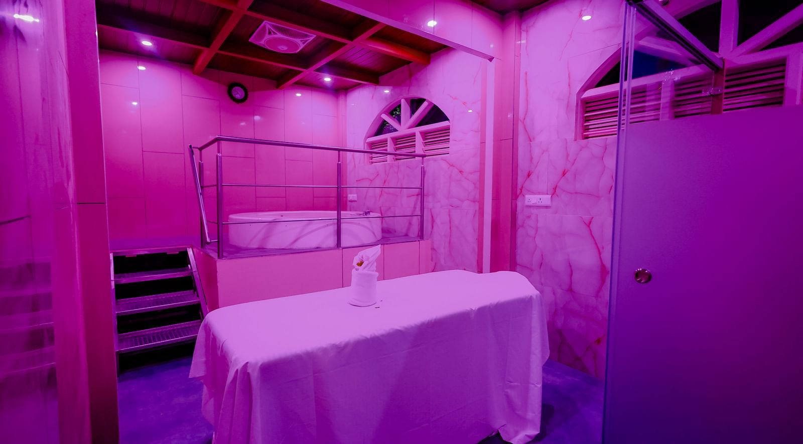 A room with a white bathtub and purple lighting at Nirantara Resort & Spa.