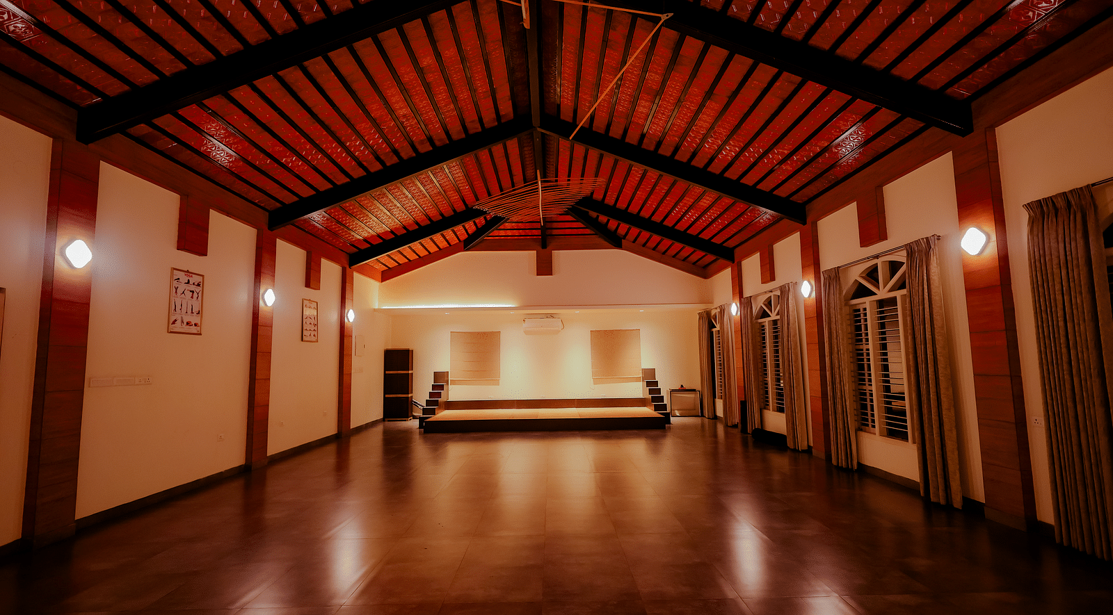 An empty event space or hall with a high ceiling and wooden floor at Nirantara Resort & Spa.