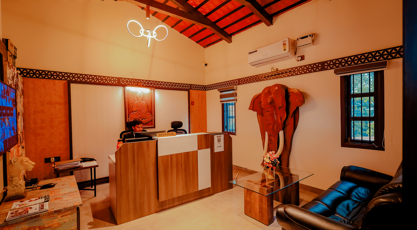 The interior of a building with a reception desk and seating area at Nirantara Resort & Spa, featuring a rustic design with wooden elements.