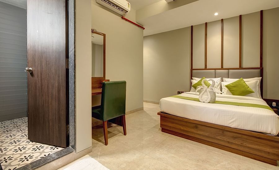 alt-text A double bed with a study table next to it inside Classic AC Room - Fortune House, Magarpatta