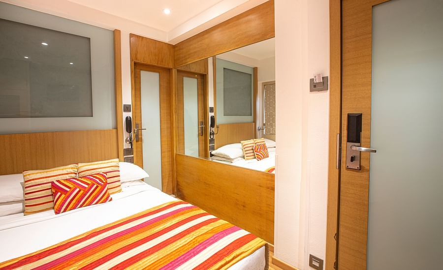 A side angle view of an economy room featuring a comfy bed and a dressing table, highlighting a cozy and inviting atmosphere.