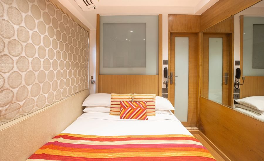 A front view of an economy room showcasing a comfy bed adorned with pillows and a blanket, creating a welcoming and cozy atmosphere.