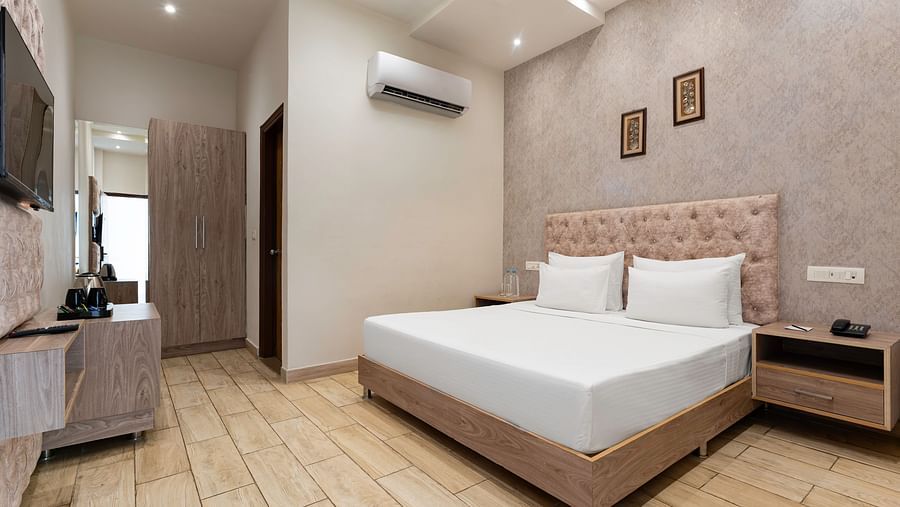 A hotel room includes a bed with a wooden headboard and a small table - SPT Clarks Inn Suites, Mandi