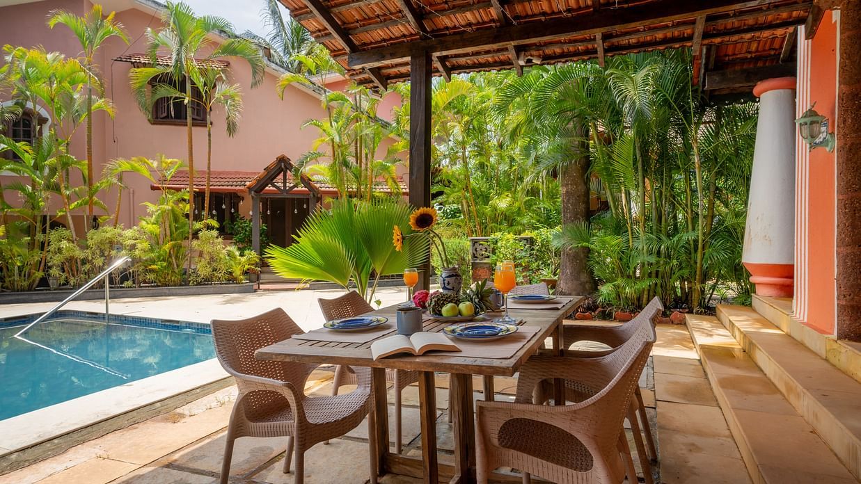 Image of a dining setting with a large table and chairs placed next to the pool