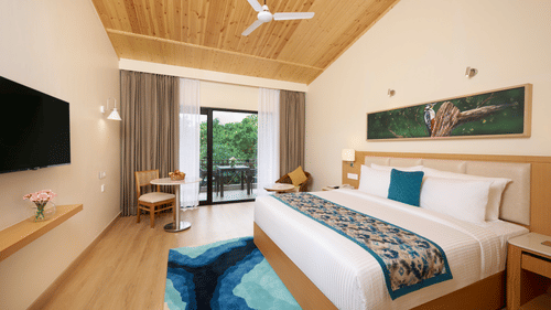 a double bed, television,  and balcony in the Premium room at ABN Sarovar Portico, Jim Corbett