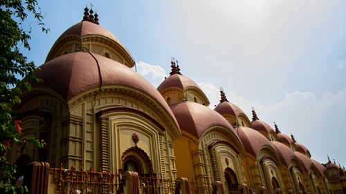 a facade view of the famous Dakshineswar Kali Temple with pagoda shaped roofs captured during the day.