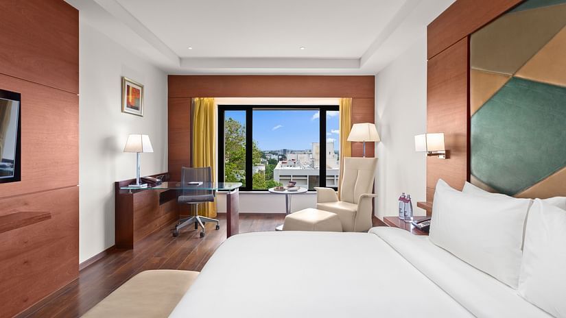 Executive Room Pool View with a cozy bed, work station with a table and lamp, and window view at The Residency Towers Coimbatore