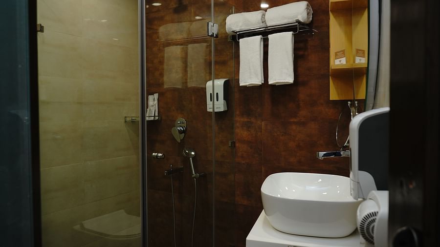 An image of a washroom featuring a sink and faucet, towels, shower glass, jet spray, and other bathroom amenities at Five Elements Hotels North Avenue, Delhi