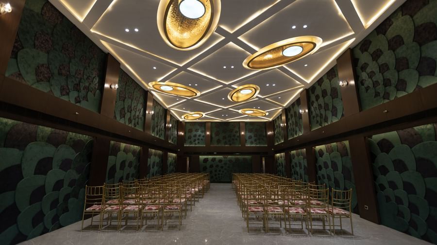 A stylish conference hall at Pride Resort, Jodhpur, with rows of chairs and an artistic ceiling featuring circular lights.