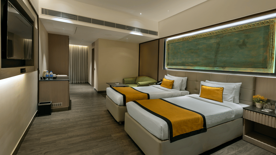 Bright guest room with twin beds, work desk and large window at The Sonnet, Jamshedpur.